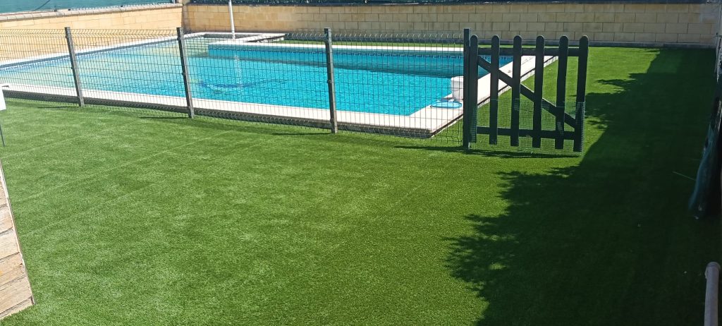 Césped artificial instalado junto a piscina con verja - Limcesped Sevilla